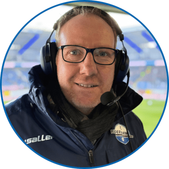 Porträt von Reporter Stefan Reddemann in der Home Deluxe Arena. Er trägt kurze blonde Haare, eine eckige Brille mit dunklem Rahmen, sowie eine dunkelblaue Winterjacke.