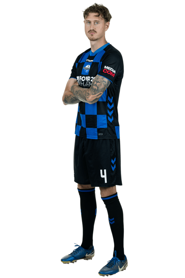 Calvin Brackelmann steht leicht nach links eingedreht mit verschränkten Armen. Er trägt das aktuelle Heimtrikot.