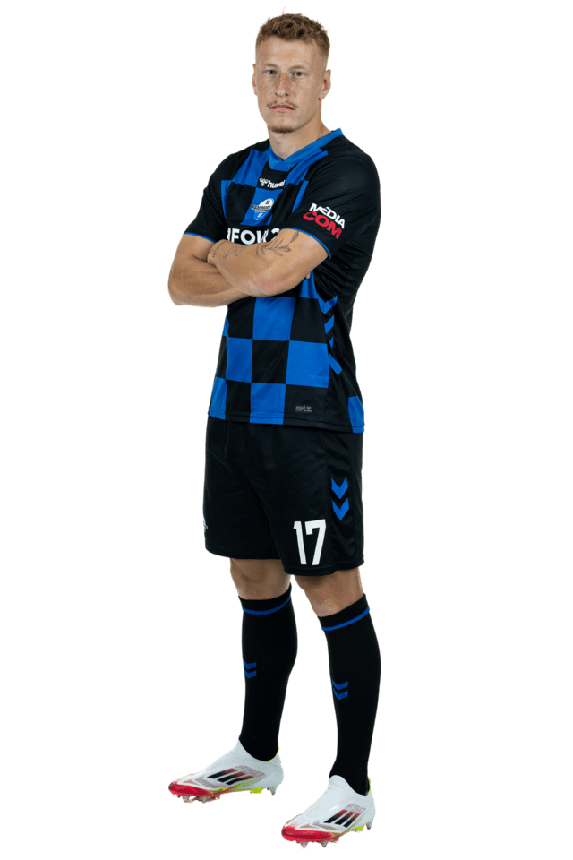 Laurin Curda steht leicht nach links eingedreht mit verschränkten Armen. Er trägt das aktuelle Heimtrikot.